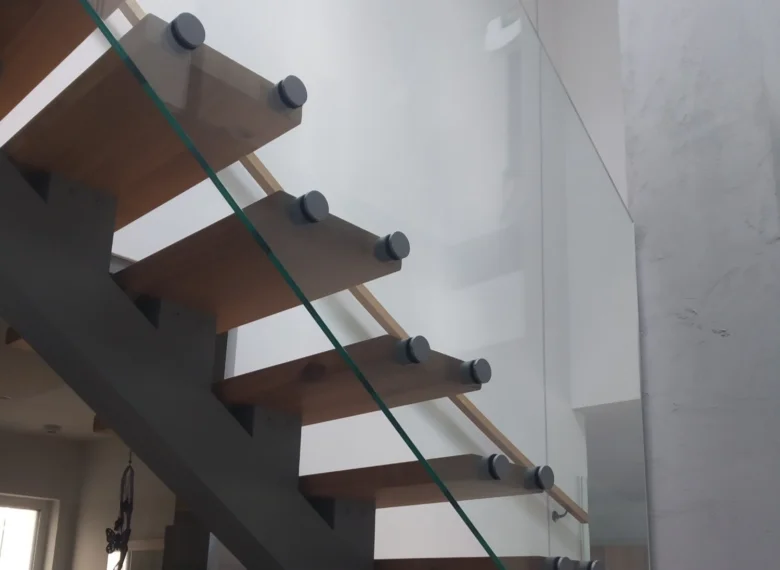 Moderní schodiště s dřevěnými stupni a skleněným zábradlím.