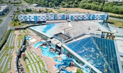 Vzdušný pohled na bazénový komplex s vnitřními i venkovními plaveckými basény.
