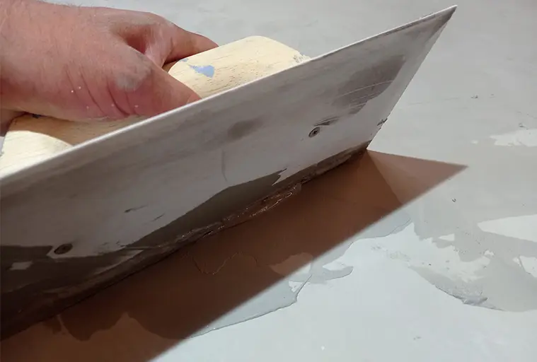 Ruční rozšiřování mokrého mikrocementu špachtlí na povrch.