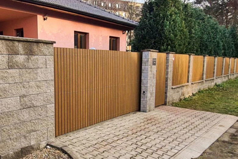 Moderní dřevěný plot s kamennými pilíři u domu.