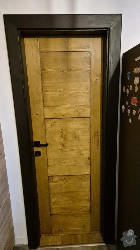 Dřevěná dveře s tmavým rámem po renovaci v interiéru.