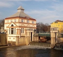 Malá vodní elektrárna s přehradou a budovou u řeky v Česku.