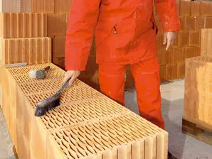 Pracovník manipulující s řadou stavebních cihel na paletě.