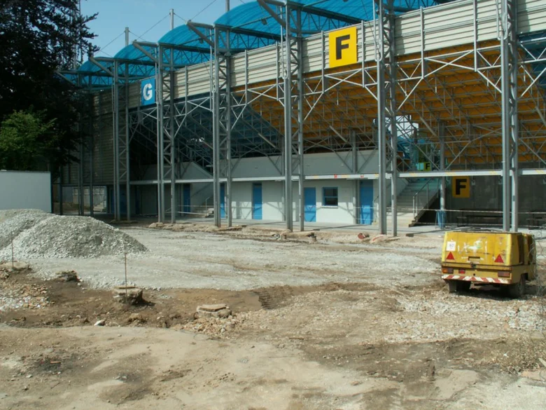 Stavební areál s částmi stadionu v pozadí.
