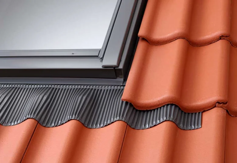 Detailní pohled na montáž střešního okna mezi taškami.