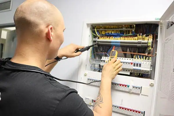 Elektrikář opravuje rozvaděč v domácnosti pomocí multimetru.