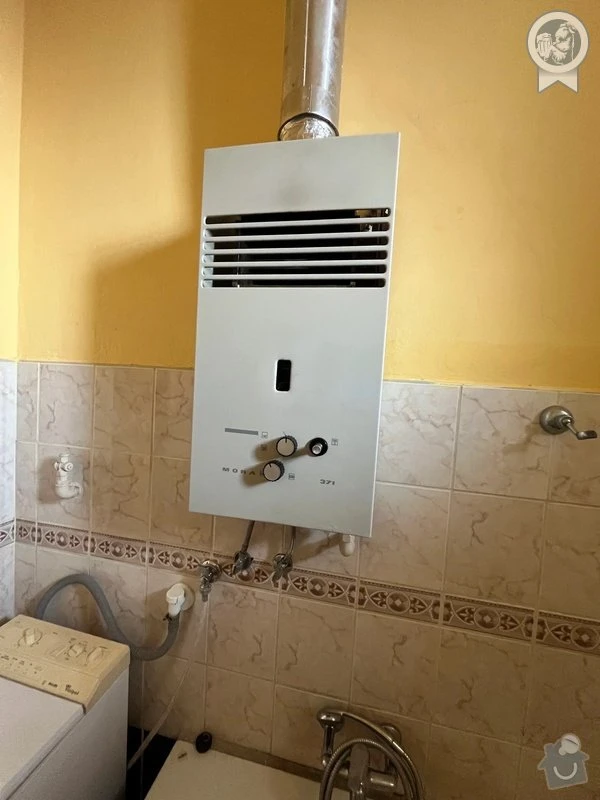 Plynový kotel na zdi v koupelně s hadicemi a ovládacími prvky.