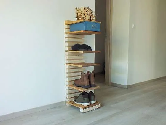 Dřevěný botník s obuví a modrým krabicovým úložným prostorem.