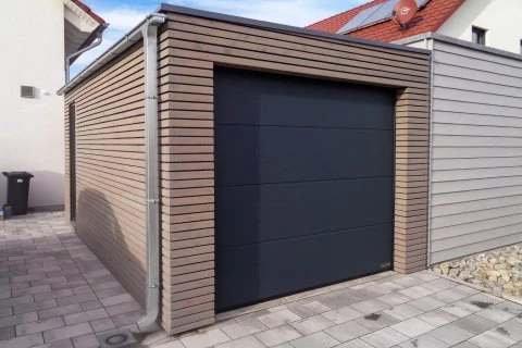 Moderní garáž s tmavými dveřmi a dřevěným obkladem.