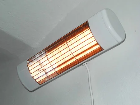 Bílý přímotop s rozžhavenými topnými prvky na zdi.