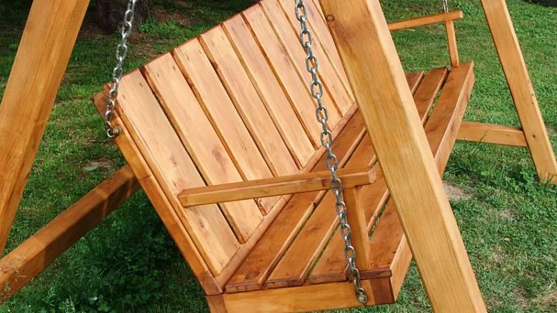 Dřevěná houpačka na zahradu s kovovými řetězy.