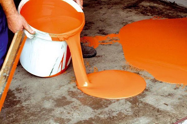 Nalévání oranžové epoxidové stěrky na betonovou podlahu.