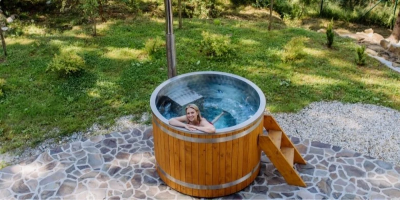 Dřevěný horký bazén s ženou v termální vodě venku