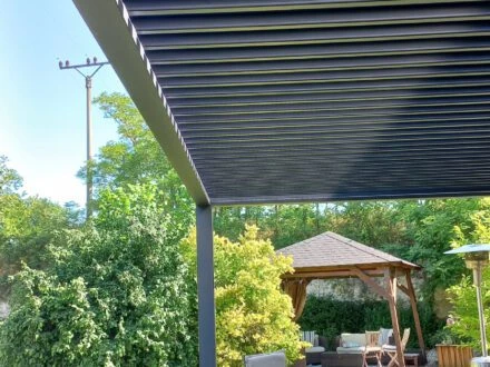 Bioklimatická pergola s nastavitelnými lamelami nad zahradním posezením.