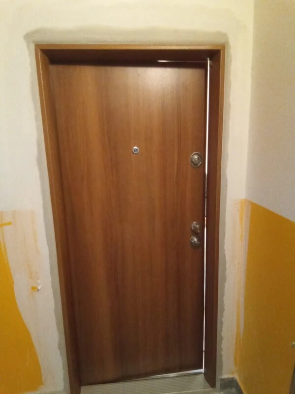 Dřevěná vstupní dveře do bytu s montáží v interiéru.