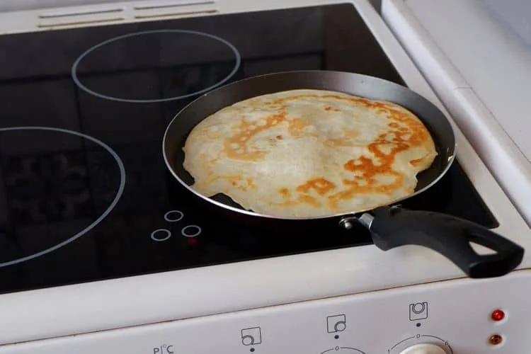 Zlatavý palačinka se vaří v pánvi na indukční varné desce.
