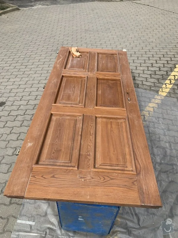 Stará dřevěná dveřní deska připravená na opravu venku.